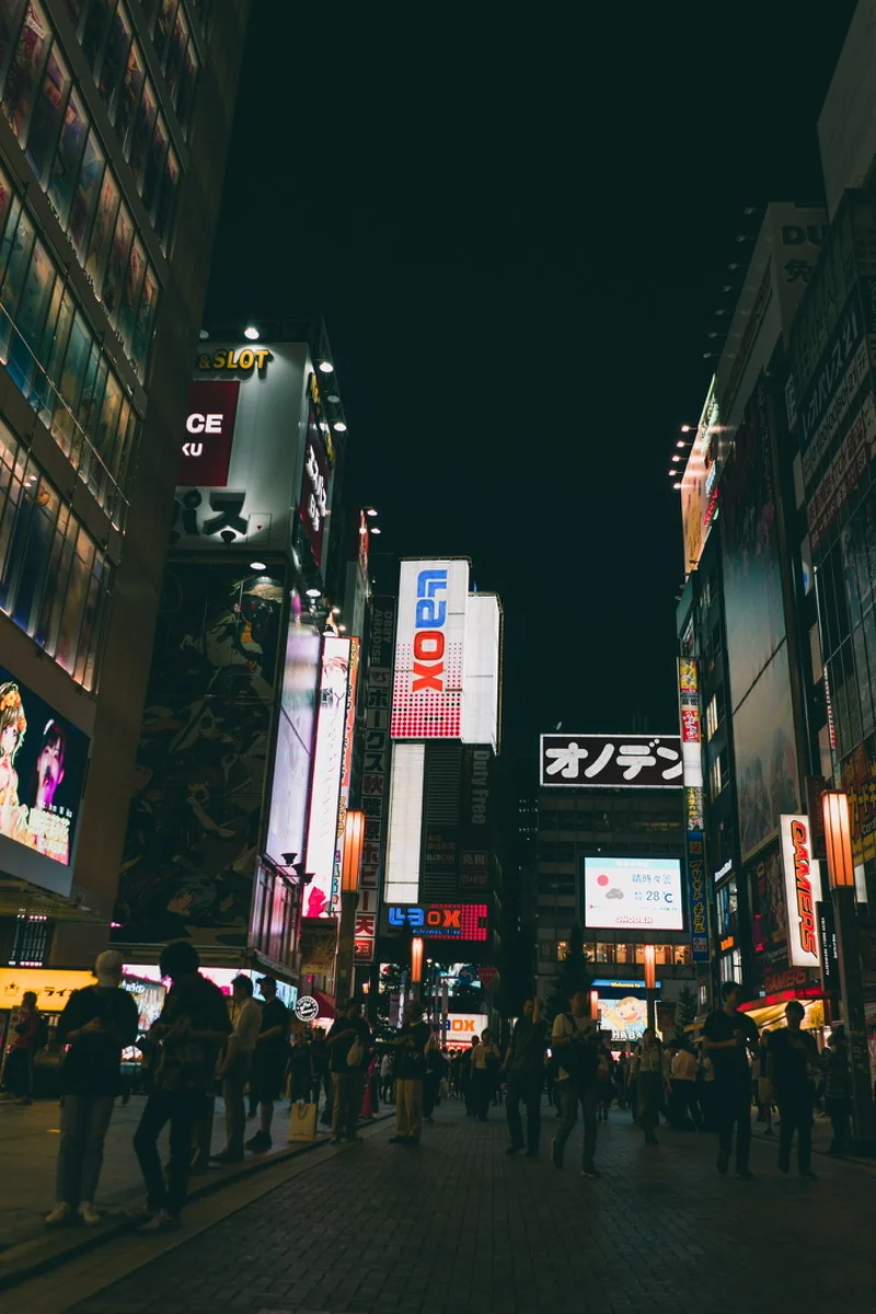 Illuminated signs above a crowded city street at night.
