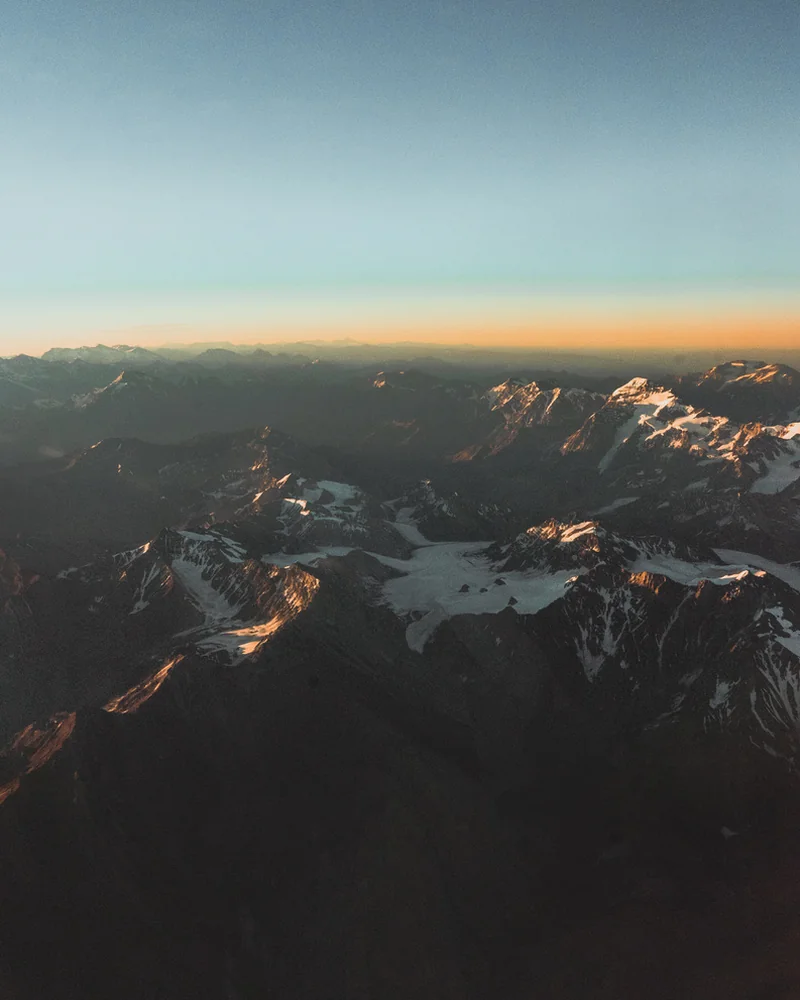 Snow-covered mountain peaks catching warm light beneath a blue sky.